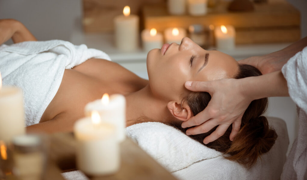 Femme recevant un head spa en institut de beauté dans une ambiance relaxante avec bougies
