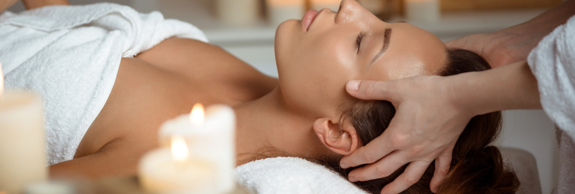 Femme recevant un head spa en institut de beauté dans une ambiance relaxante avec bougies