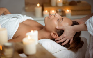 Femme recevant un head spa en institut de beauté dans une ambiance relaxante avec bougies