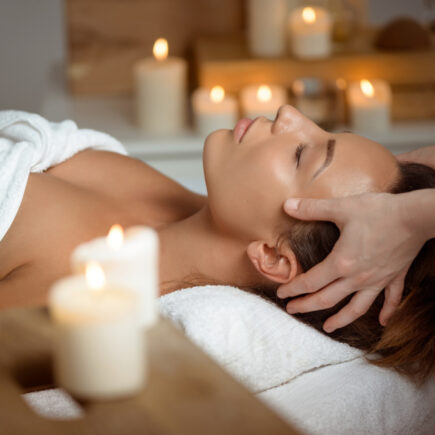 Femme recevant un head spa en institut de beauté dans une ambiance relaxante avec bougies