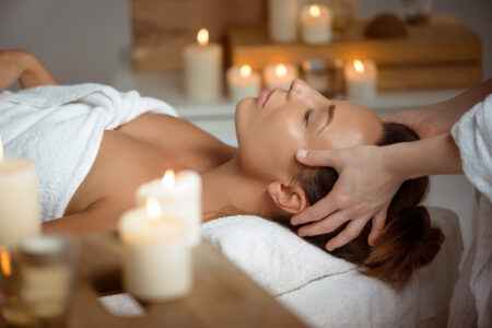 Femme recevant un head spa en institut de beauté dans une ambiance relaxante avec bougies