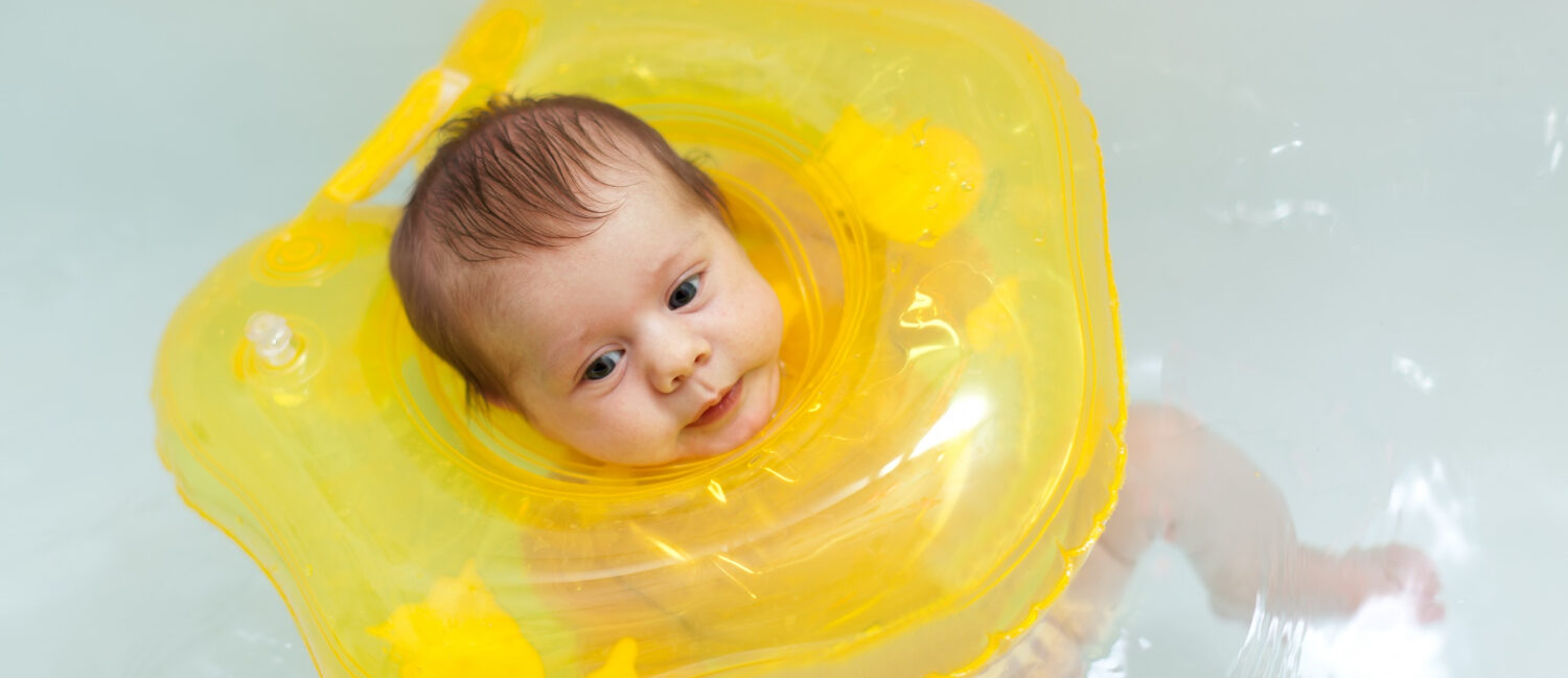Nourrisson qui flotte calmement dans l'eau d'un baby spa avec une bouée de cou jaune pour améliorer son sommeil