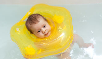 Nourrisson qui flotte calmement dans l'eau d'un baby spa avec une bouée de cou jaune pour améliorer son sommeil