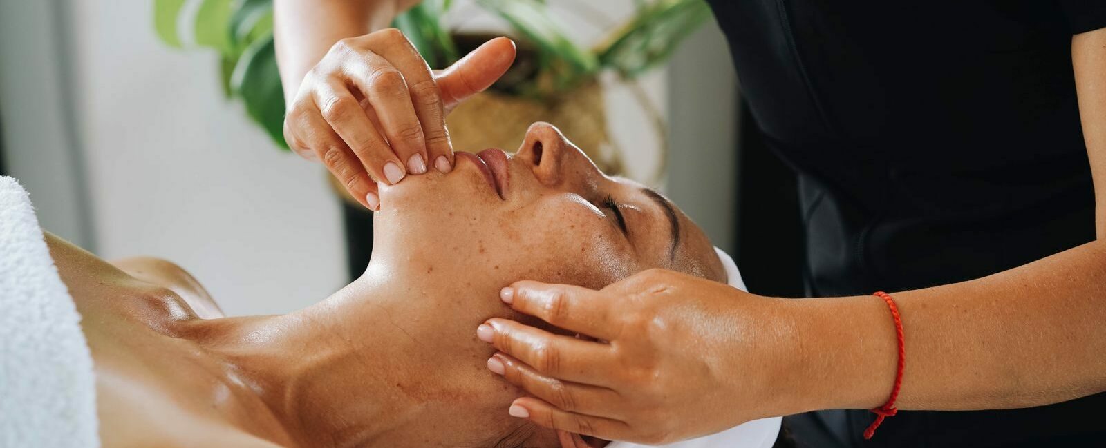 Esthéticienne réalisant un massage facial Kobido anti-âge et un drainage du visage en institut