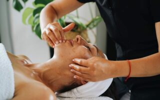 Esthéticienne réalisant un massage facial Kobido anti-âge et un drainage du visage en institut