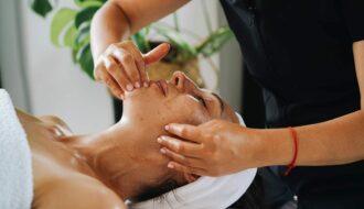 Esthéticienne réalisant un massage facial Kobido anti-âge et un drainage du visage en institut
