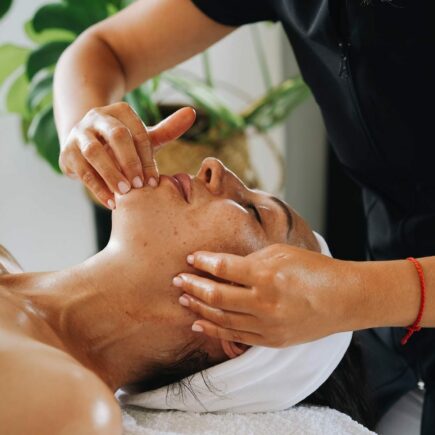 Esthéticienne réalisant un massage facial Kobido anti-âge et un drainage du visage en institut